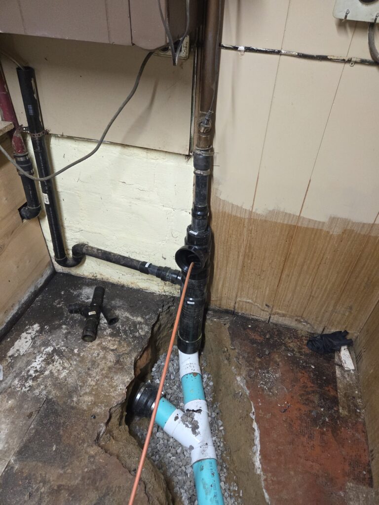 Repaired kitchen drain stack with an open cleanout above the new underground connection.